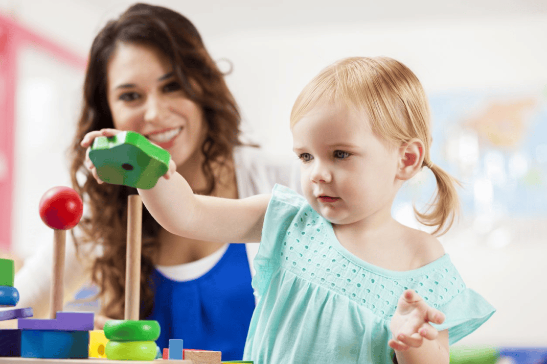 A young girl is playing with a toy in a playroom.