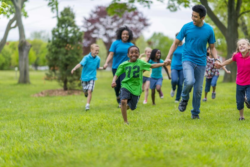 Adults and kids holding hands and racing.